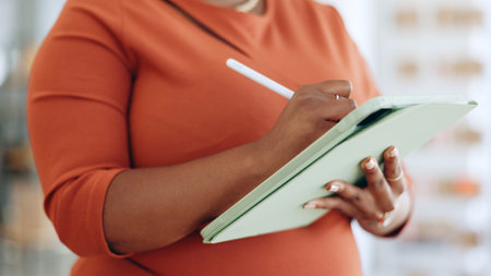 Woman, hands and tablet writing schedule, planning or digital notes for marketing, research or advertising at office. Hand of female working on touchscreen, mobile app or strategy at the workplaceの写真素材