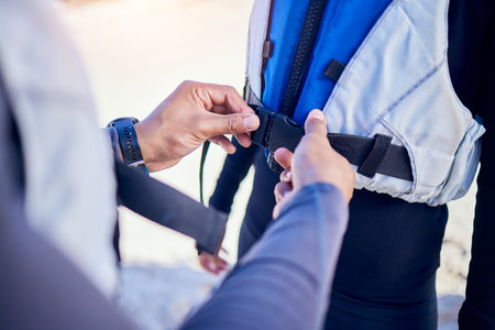 Person, hands and helping with life jacket for safety, security and people prepare for water, boat and journey on river with protection. Lake, lifejacket or adventure with man and woman in vestの写真素材