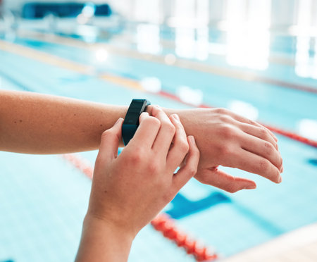 Stopwatch, person or hands of swimmer at swimming pool for sports, workout or fitness progress. Personal trainer, exercise or closeup of athlete with timer to check or monitor clock goal or heartbeatの写真素材