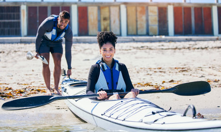 Sports, portrait or man and woman in kayak on sand at lake, beach or river for exercise on vacation. Ocean holiday, water adventure or fitness for happy couple in canoe training or workout with smileの写真素材
