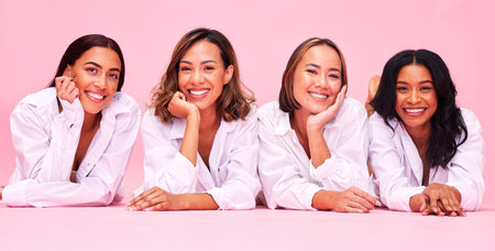 Portrait, smile and lingerie with woman friends on a pink background in studio for natural skincare. Diversity, beauty and wellness with a female model group posing for health, inclusion or cosmeticsの写真素材