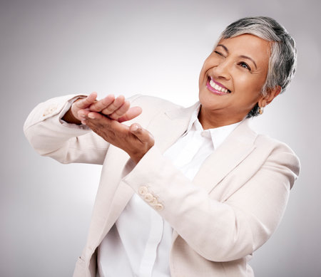 Smile, money gesture and senior woman in a studio with cashback, prize or financial freedom. Happy, excited and elderly female model with finance hand sign or emoji for savings by a gray background.の写真素材