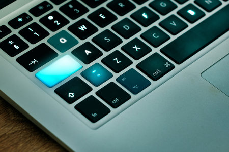 Laptop, keyboard and shift key glow on a desk closeup for networking, typing or blogging in an...