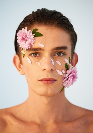 Floral, skincare and flowers with portrait of man in studio for beauty, natural cosmetics and creative. Glow, self love and spring with face of model on white background for makeup, spa and wellnessの写真素材