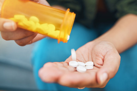 Hand, bottle and pills, closeup of drugs for health and sick person, wellness supplements and vitamins. Healthcare, pharmaceutical tablet and plastic container, antibiotics and treatment for illnessの写真素材