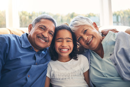 Grandparents, portrait and happy kid in home living room on sofa, bonding or having fun together. Face, grandmother and grandfather with child in lounge to relax with love, care and family connectionの写真素材