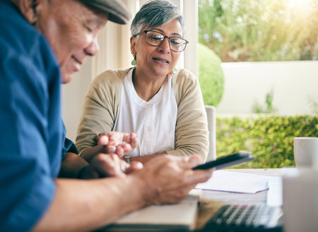 Phone, finance or old couple with budget paperwork, mortgage or banking documents at home. Bills, mature woman or senior man speaking of financial debt, investment portfolio or planning taxes costの写真素材