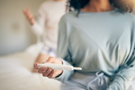 Hands, woman and bed with pregnancy test, closeup and home for results, planning or news to start family. Girl, exam and notification in bedroom, apartment and anxiety for maternity, future or babyの写真素材