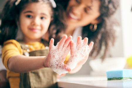 Soap, cleaning hands and family with child in bathroom for learning healthy hygiene routine at home. Closeup, mom and girl kid washing palm with foam for safety of bacteria, dirt or germs on skincareの写真素材