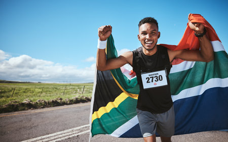 Portrait, sports and flag of South Africa with a man running on a street in nature for motivation or success. Fitness, winner or celebration with a runner cheering during cardio or endurance trainingの写真素材