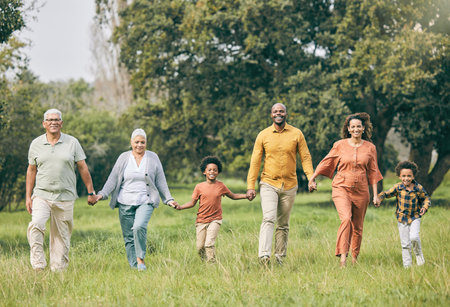 Portrait, holding hands and happy family at a park walking, bond and having fun in nature together. Love, smile and children with parents, grandparents and freedom, support and trust on forest walkの写真素材