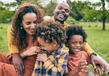Happy black family, parents and children in a park in summer, smile and relax on grass field for love and fun in nature. Happiness, picnic and portrait of African people outdoor and playing togetherの写真素材