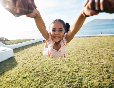 Girl, spin and outdoor portrait in pov, holding hands or happy for game with parent, holiday or backyard. Female child, smile and swing in air, fast or excited for play on vacation in summer sunshineの写真素材