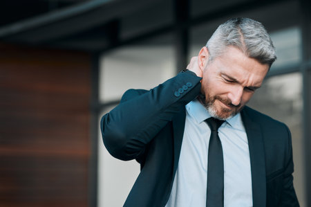 Tired, mature and a businessman with neck pain in the city from work stress, problem or accident. Sad, medical emergency and a ceo or manager with a muscle injury, frustrated or professional fatigueの写真素材