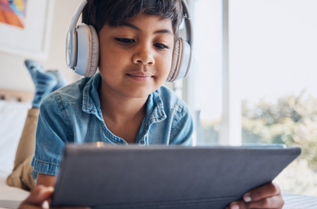 Boy kid, tablet and headphones on bed, reading or idea with e learninng, movie and relax with web...