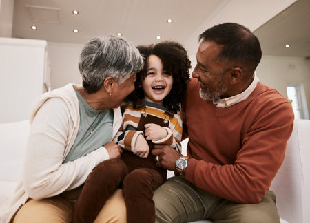 Grandparents love, laugh and happy family child, grandma and grandfather excited, having home fun and babysitting grandchild. Comedy humour, grandfather and grandmother play with kid on lounge sofaの写真素材