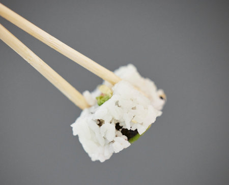 Seafood, sushi and chopsticks on studio background, California roll with seaweed for healthy Asian dining promo. Japanese food culture with rice, raw fish and avocado, restaurant menu offer or deal.の写真素材