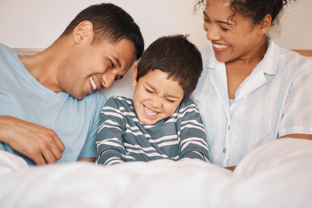 Happy, tickle and funny with family in bedroom for playful, morning and love. Care, support and wake up with parents and boy child laughing in bed at home for weekend, positive and relax togetherの写真素材