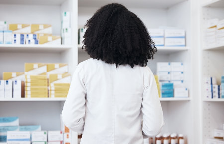 Healthcare woman, pharmacy and medicine on shelf with pills or medication for inspection or inventory. Back of pharmacist person or medical staff to check stock or pharmaceutical product at drugstoreの写真素材