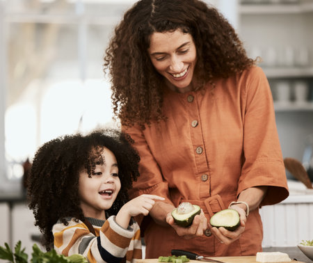Family, avocado and a mother cooking with her daughter in the kitchen of their home together for...