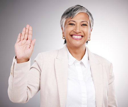Smile, wave and portrait of a woman on a studio background for hello, welcome or a pledge. Happy, mature and a corporate manager or person with a hand for greeting or thank you on a backdropの写真素材