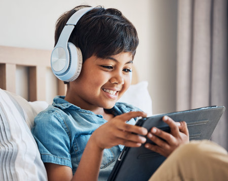Happy, kid and headphones with tablet in bedroom to watch movies, video game and elearning app. Boy...