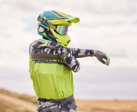 Motor sports, stretching and man with helmet in nature for training, workout and performance for race. Travel, motorbike and person outdoors ready for action for adventure, freedom and adrenalineの写真素材