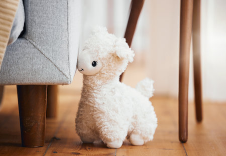 Teddy bear, empty room and toy on floor of home, background and alone by sofa in lounge of house. Abandoned, lonely and stuffed animal for grief, mental health, loss and sad or security by couchの写真素材