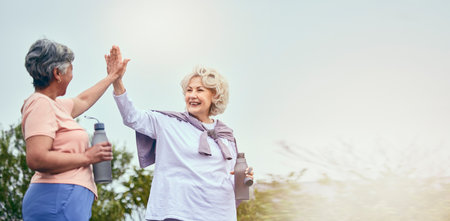 Senior women, walking and high five for motivation and workout success from outdoor fitness. Banner, elderly friends and happy from sport and exercise together with support smile and mockup spaceの写真素材