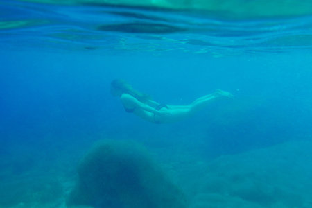 Beautiful woman swimming underwater on paradise beach freedom wellbeing lifestyle summer vacation wanderlustの写真素材