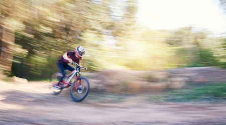 Blur, race and man cycling in nature training for a competition on trail in forest or woods. Action, sports or fast cyclist athlete riding bicycle at speed for cardio exercise, fitness or workoutの写真素材