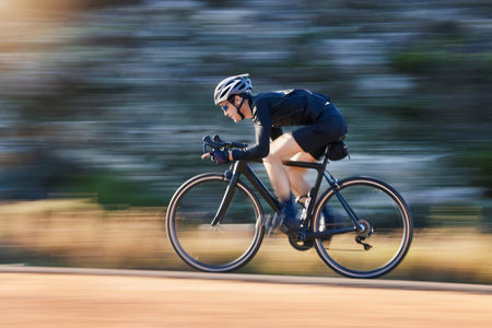 Motion blur, speed and cyclist on bicycle on road in mountain with helmet, exercise adventure trail and fitness. Cycling race, nature and man with bike for fast workout, training motivation or energyの写真素材