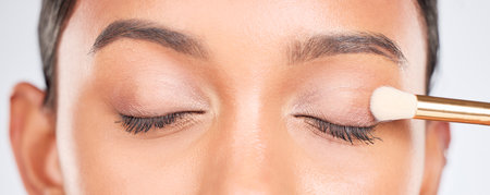 Eyes, eyeshadow and brush, woman and makeup with beauty product and tools isolated on white background. Lashes, closeup and powder, eyebrow and microblading with skin, shine and cosmetics in studioの写真素材