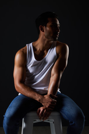 Body, muscle and sexy man on chair in studio with fitness inspiration, aesthetic and sensual fashion. Art, wellness and performance, muscular male model on black background thinking in dark lighting.の写真素材