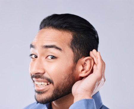Deaf, portrait and asian man with hand on cochlear in studio for speak up, listen or communication...