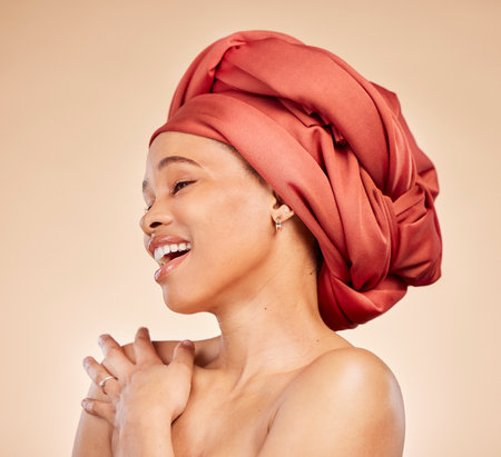 Natural beauty, woman and head wrap in studio, smile and cosmetic for skincare and face glow on beige background. Cosmetology, wellness and person with makeup for happiness, confidence and self careの写真素材