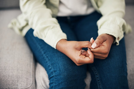 Anxiety, hands and woman on a sofa with stress, worry or mental health crisis in her home....