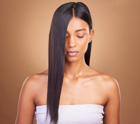 Beauty, hair and keratin with face of woman in studio for cosmetics, salon treatment and texture. Shampoo, health and growth with Indian model on brown background for glamour, shine and hairstyleの写真素材
