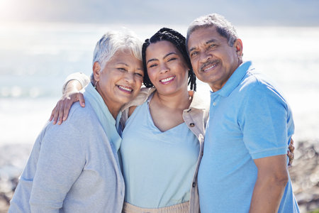 Beach, portrait and woman with her senior parents hugging and bonding on vacation together. Happy, smile and female person embracing her elderly mother and father by ocean on holiday or weekend trip.の写真素材