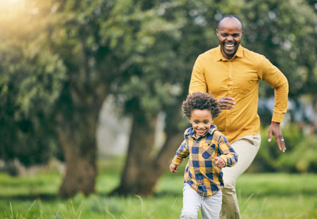 Happy father, running and child at a park with freedom to playing in nature together on holiday. Love, energy or excited kid in a forest with an African father bonding with fun active games and smileの写真素材