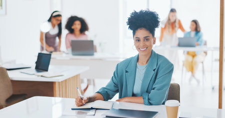 Portrait of happy woman, creative agency and writing in notebook for admin at design agency. Female designer at modern office desk, manager at startup with happiness and coworking space with notes.の写真素材