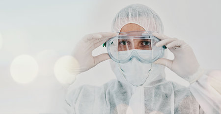 PPE, person and safety suit goggles of lab worker and healthcare professional in hospital or clinic. Cleaning, bacteria protection and face mask with virus, pharmacy and wellness research with bokehの写真素材