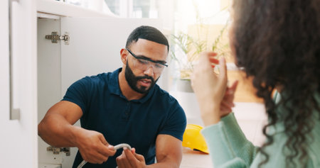 Plumber black man, woman and maintenance talk in kitchen for sink pipe with customer support in home. Entrepreneur handyman, plumbing or small business owner with consulting for fixing water systemの写真素材