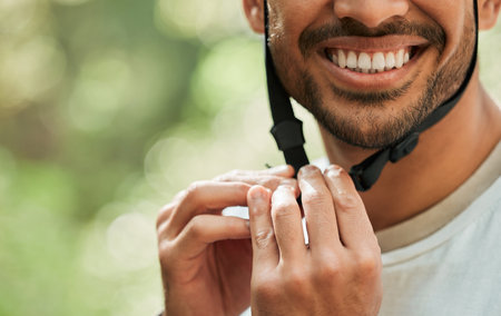 Hands, helmet and ready for cycling in forest for man, smile and buckle for training, adventure or transport. Guy, closeup and happy with ppe, countryside and preparation in woods, park or natureの写真素材