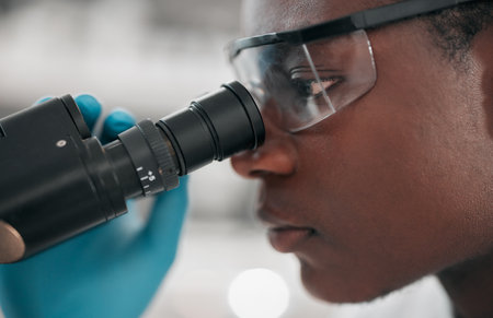 Microscope, black man and healthcare with research, medical and dna test with biotechnology. African person, science and researcher with laboratory equipment, check sample and vaccine with analyticsの写真素材