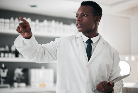 Tablet, future and a science black man using a dashboard in a laboratory for research or innovation. Metaverse. technology and healthcare with a medicine professional working in a hospital labの写真素材