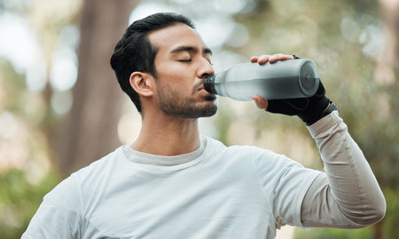 Sports, man and drinking water in park for exercise break, energy and workout rest. Thirsty athlete,...