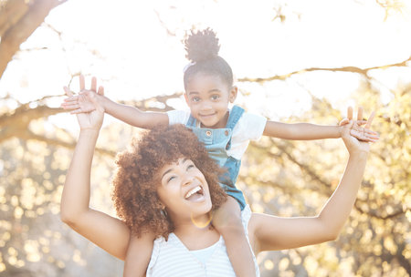 Airplane, love and mother with girl child in a park happy, freedom and adventure in nature together. Flying, piggyback and kid with mom in a forest for games, travel or explore with care and supportの写真素材