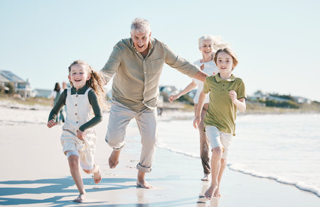 Running, happy and grandparents with children on beach for energy, freedom and summer vacation. Love, relax and travel adventure with family on seaside holiday for health, bonding and games togetherの写真素材