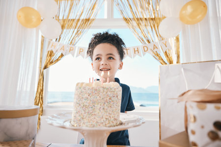 Birthday party, cake and smile with child and candles for celebration, food and dessert. Excited, balloons and happy with young boy making wish in family home for surprise, gift and holiday eventの写真素材